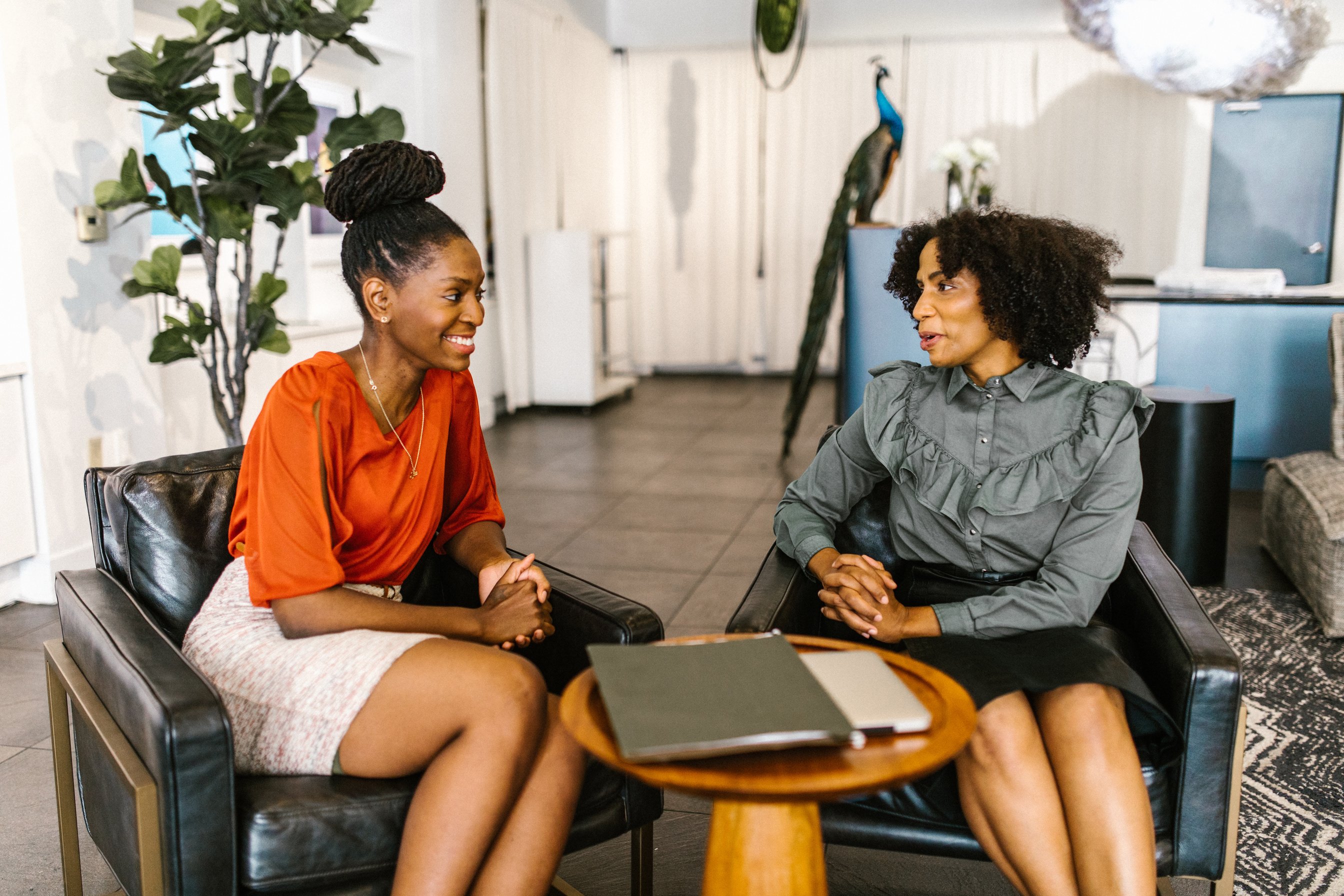 Women Sitting on a Black Chair while Having Conversation